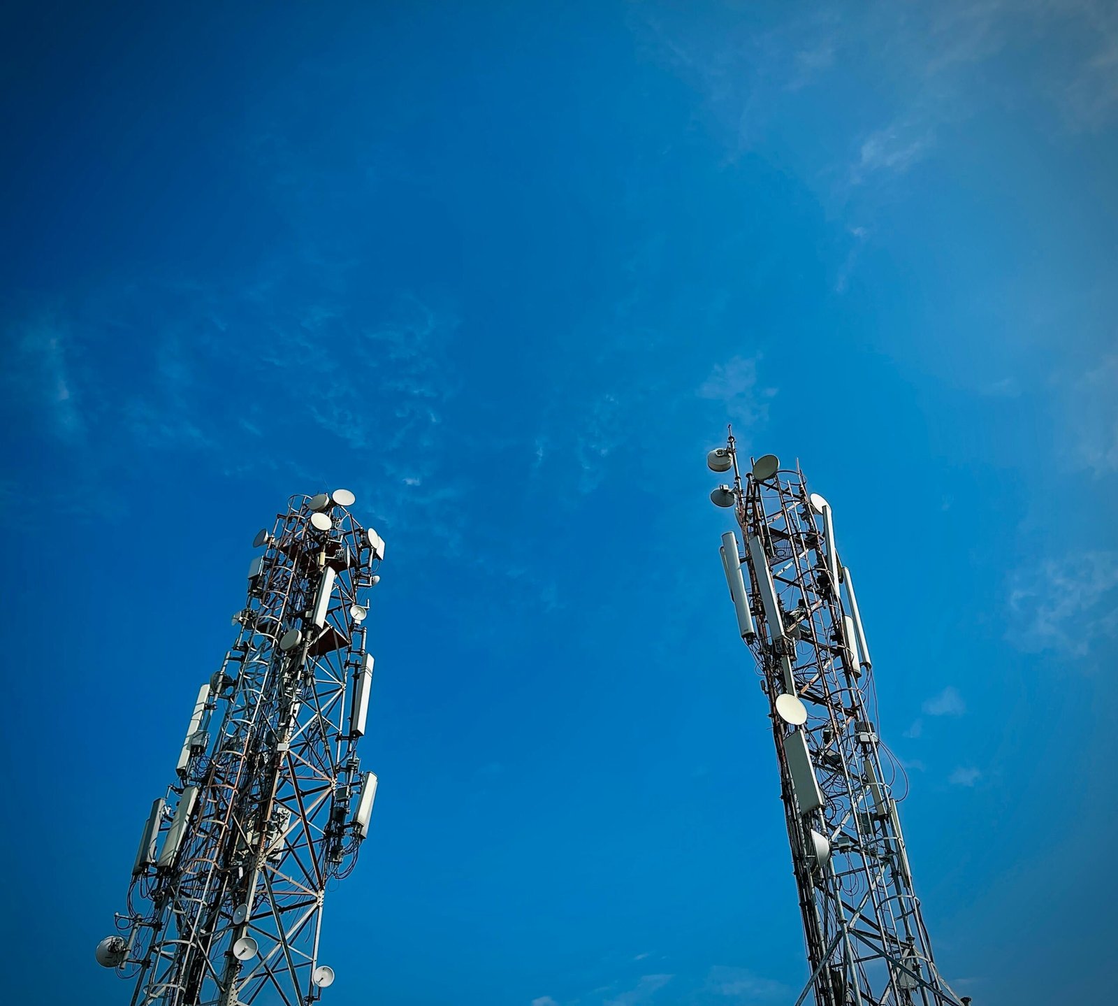 Two telecommunication towers standing against a vibrant clear blue sky, showcasing modern communication technology.